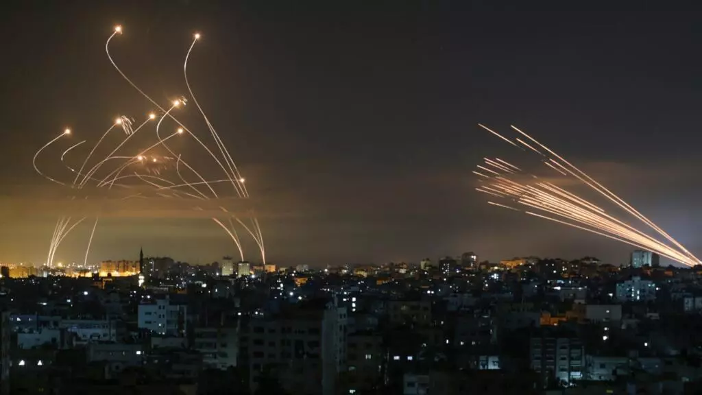 El sistema israelí de defensa de misiles, Cúpula de Hierro, (izquierda) intercepta cohetes (derecha) disparados por el movimiento Hamas hacia el sur de Israel, desde Beit Lahia en el norte de la Franja de Gaza, durante la noche del 14 de mayo de 2021.